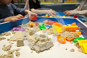 Kids playing plastic mold toys with sand on sandbox.