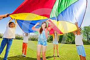 Kids playing with rainbow parachute in the park