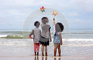 Kids playing running on sand at the beach, A group of children holding hands in a row on the beach in summer, rear view against