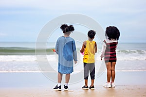 Kids playing running on sand at the beach, A group of children holding hands in a row on the beach in summer, rear view against