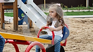 Kids playing at the see-saw in the playground. Children have fun in summer