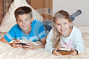 Kids playing with smartphone on a bed