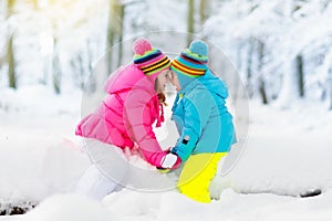 Kids playing in snow. Children play outdoors in winter snowfall.