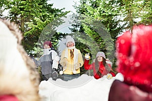 Kids playing snowballs hiding behind snow tower