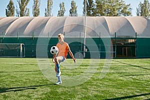 Kids playing soccer game, young boy footballer wearing uniform hitting ball