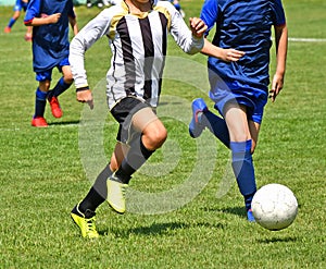 Kids are playing soccer outdoor in summer time