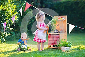 Kids playing with a toy kitchen in a summer garden