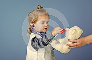 Kids playing with toys. Boy doctor examine toy pet with stethoscope on blue background