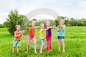 Kids playing with water guns on a meadow