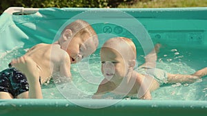 kids in pool having fun happy family concept. two male siblings splash in water