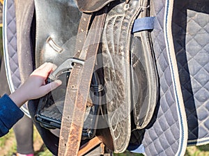 Kids preparing stirrup and lower abdomen on saddle