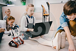 kids programming robot while sitting on floor at stem