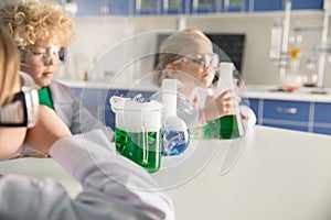 Kids in protective glasses and lab coats making experiment