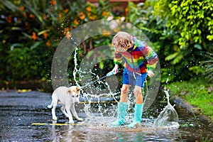 Kids in puddle in autumn rain. Waterproof wear