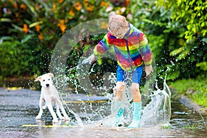 Kids in puddle in autumn rain. Waterproof wear