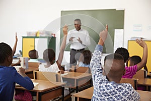 Kids raising hands during a lesson at an elementary school