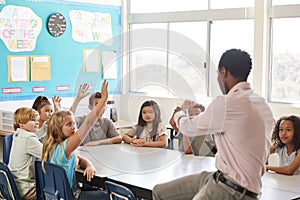 Kids raising hands to answer in an elementary school lesson