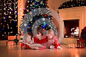 Kids reading a book on Christmas eve at fireplace