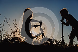 Kids riding bike and scooter at sunset