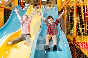 Kids riding from childrens slides in game center photo