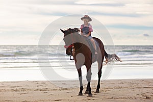 Kids riding horse on beach. Children ride horses