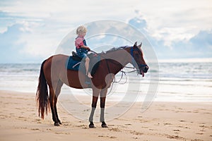 Kids riding horse on beach. Children ride horses