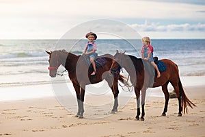 Kids riding horse on beach. Children ride horses