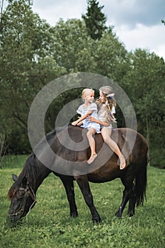 Kids riding horse in the mountains. Family vacation on horse ranch. Children ride horse. Child and pet. Little girls