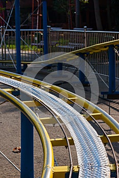 Kids roller coaster yellow rails in amusement park.