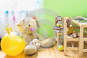 Kids Room Interior with Wooden Furniture Set. Teddy Bear on Chair Big Plush Toys Books Crayons on Table.