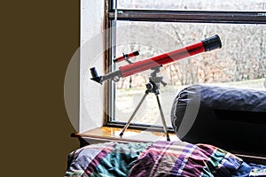 Kids room - Telescope in window over bed with plaid wrinkled comforter - Close-up and Copy Space