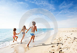 Kids running along beach during summer vacation