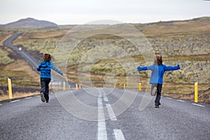 Kids running on an empty road in beautiful nature in Snaefellsjokull National Park in Iceland, autumntime