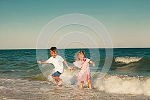 A kids running on the seashore with waves