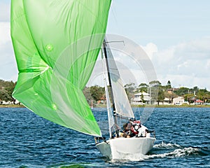 Kids sailing small sailboat head-on closeup with a fouled green spinnaker