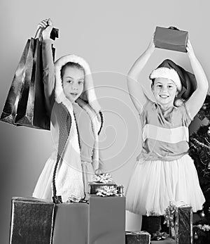 Kids in Santa Claus hats with gift boxes hold presents