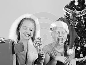 Kids in Santa Claus hats with gift boxes open presents.