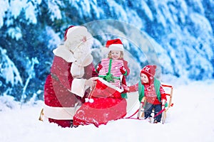 Kids and Santa Claus opening presents in snowy forest