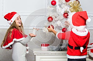 Kids in santa hats decorating christmas tree. Family tradition concept. Children decorating christmas tree together