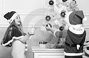 Kids in santa hats decorating christmas tree. Family tradition concept. Children decorating christmas tree together