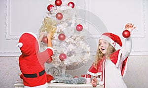 Kids in santa hats decorating christmas tree. Family tradition concept. Children decorating christmas tree together. Boy