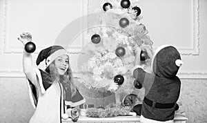 Kids in santa hats decorating christmas tree. Family tradition concept. Children decorating christmas tree together. Boy