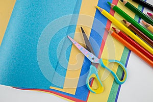 of kids scissors colored paper and pencils