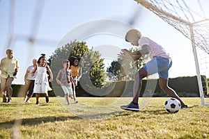 Kids scoring goal against dad during family football game