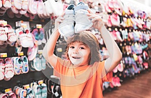 Kids shoes store in supermarket, choosing kids in shoes store. Shoes store for kids. Kid in supermarket shoes shop. Sale