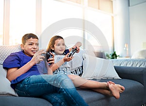 Kids, siblings and video game with controller, sofa and online for esports in home. Technology, entertainment and