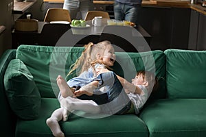 Kids sister and brother laughing tickling on sofa playing togeth