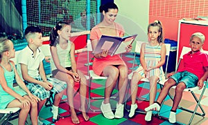 Kids sitting around teacher reading book