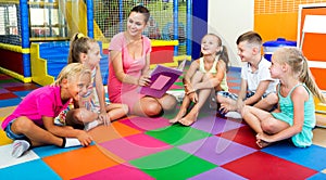 Kids sitting around teacher reading book