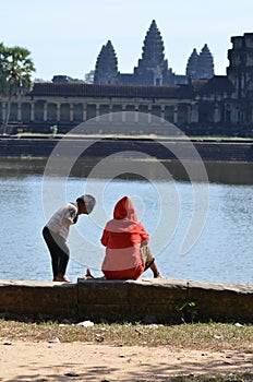 Kids sitting in front of Angkor Wat Cambodia ruin historic khmer temple
